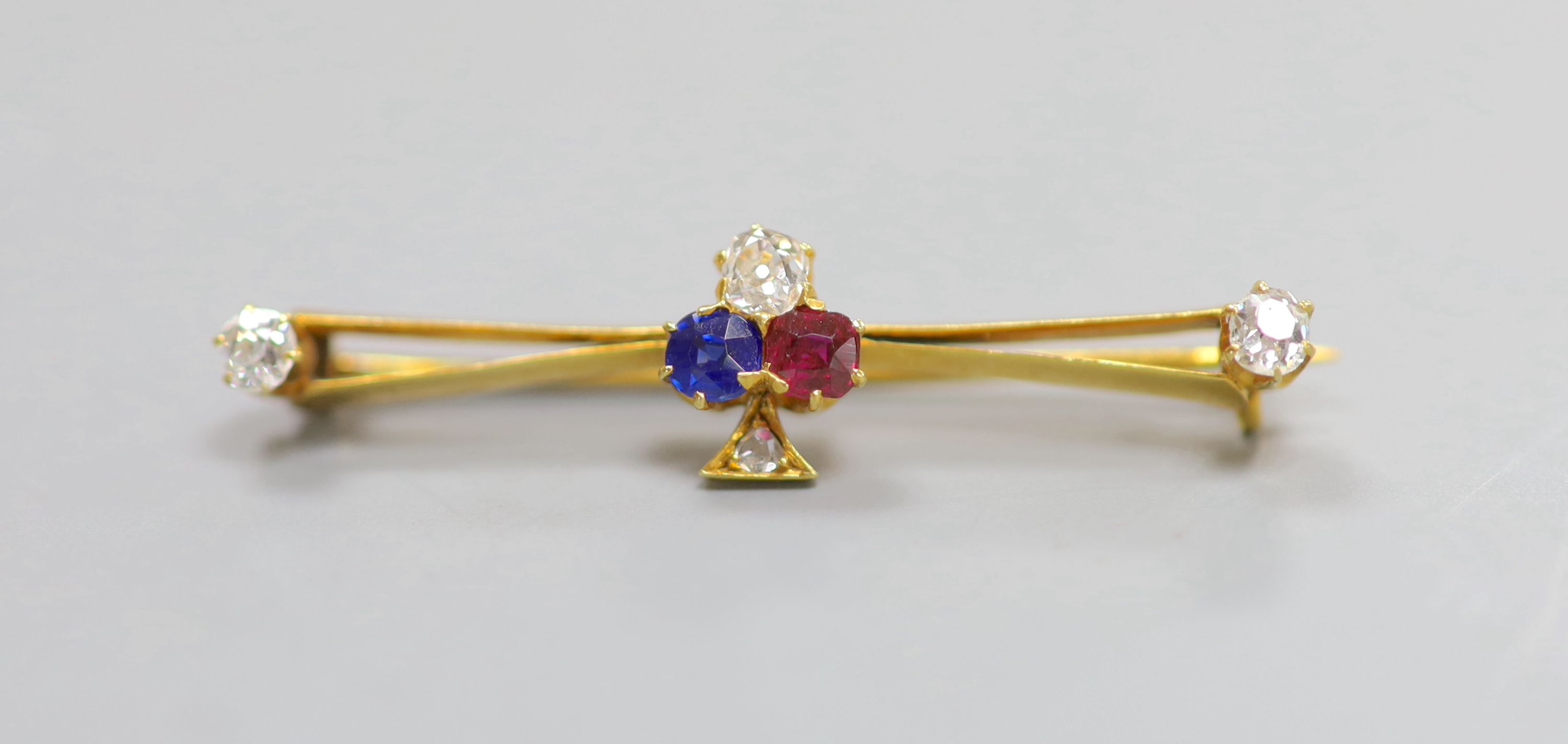 An Edwardian yellow metal, ruby, sapphire and diamond set clover bar brooch